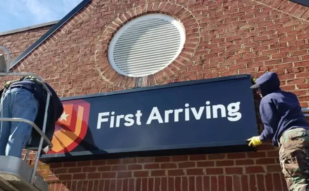A First Arriving sign being installed on a building