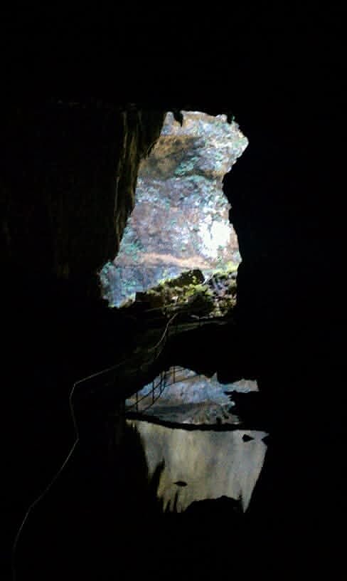 A cave opening mirrored in still water