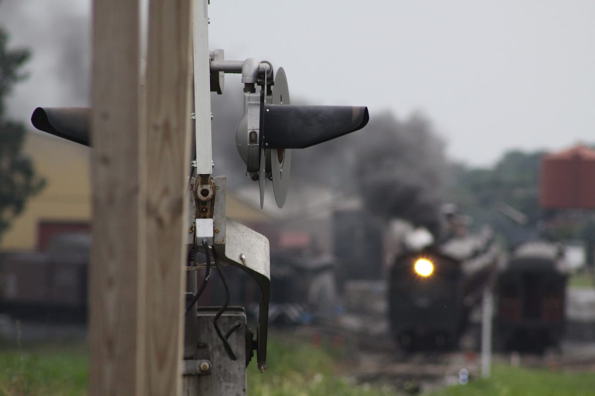 A steam locomotive behind a railroad signal
